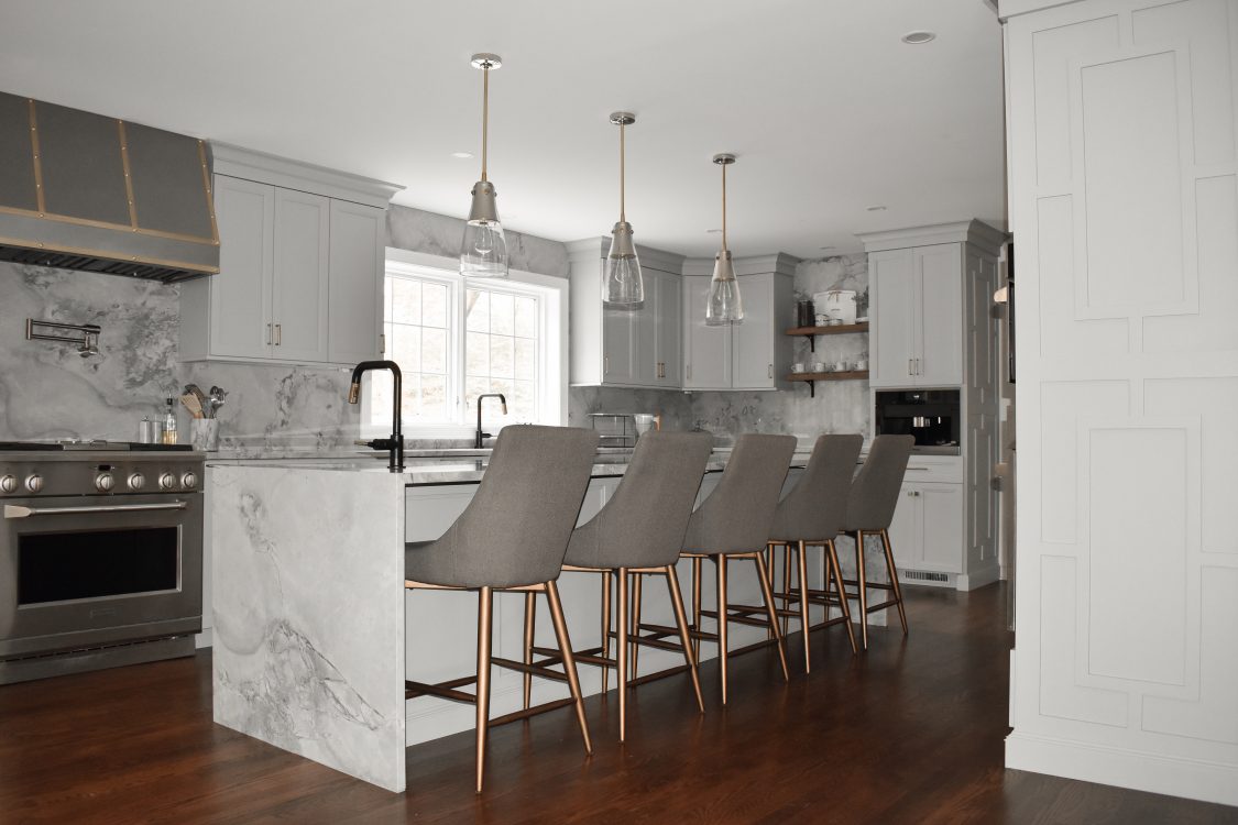 A modern kitchen in with white cabinets and matching marble walls and countertops