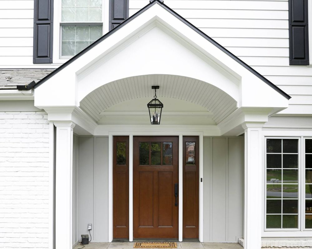 white overhang over brown fiberglass front door and a small light hanging underneath the overhang
