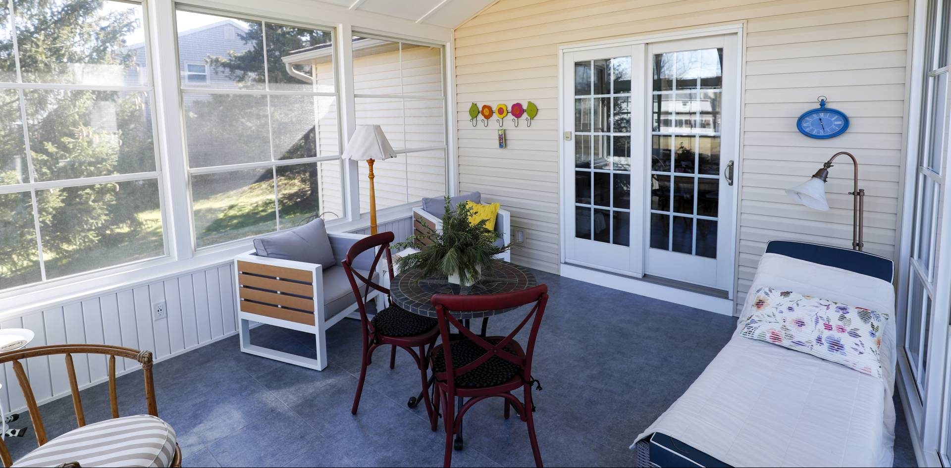all seasons room with full length windows with white trim and chairs and a small wooden table on the sunroom